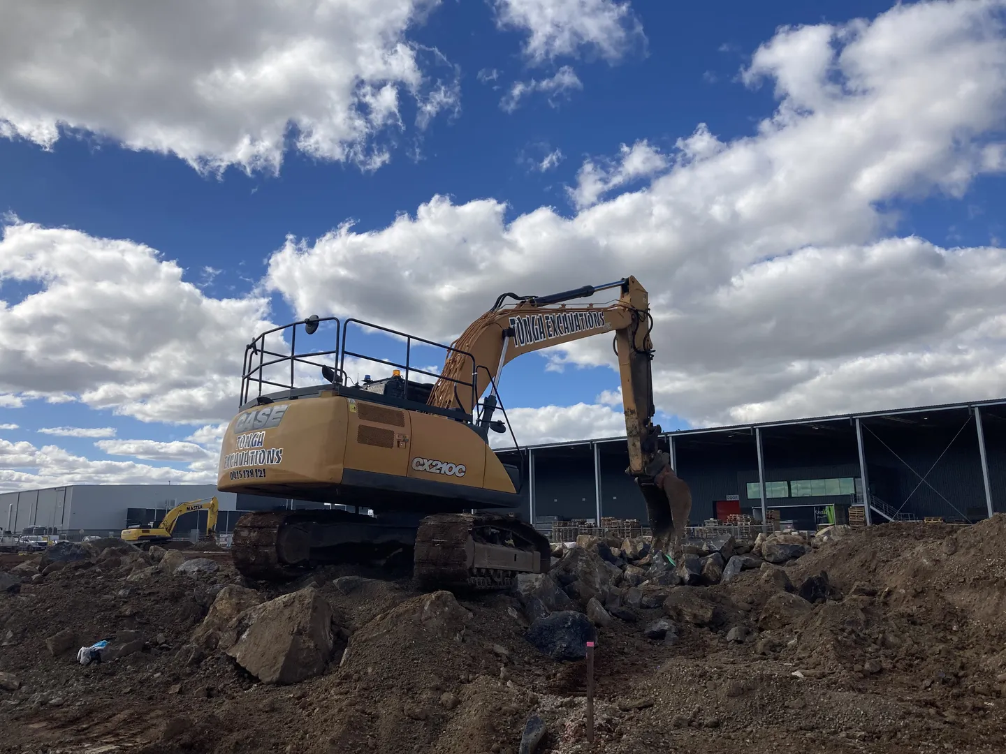 Excavator working on rocky construction site outdoors.