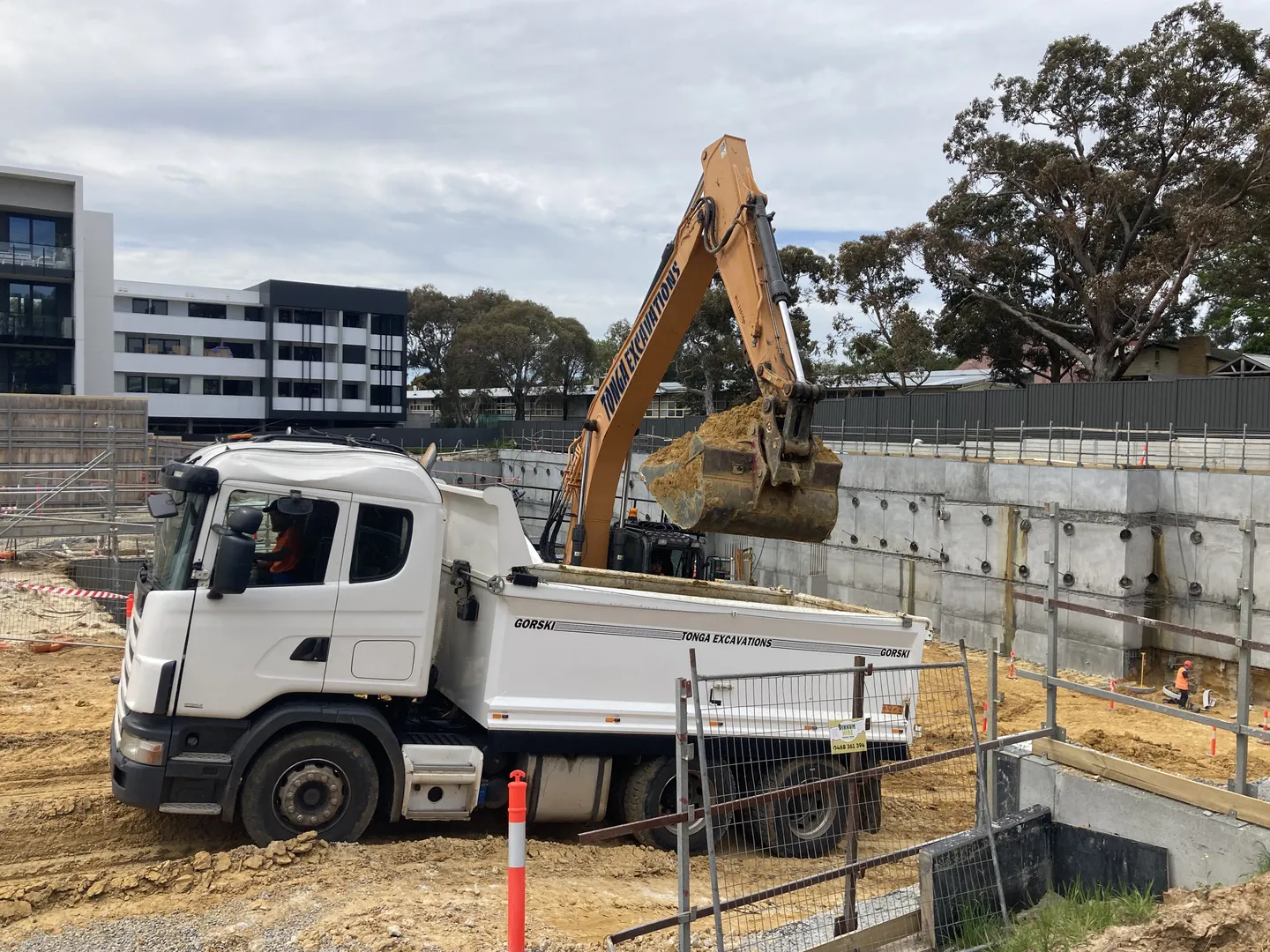 Excavator loading dirt into dump truck at construction site.