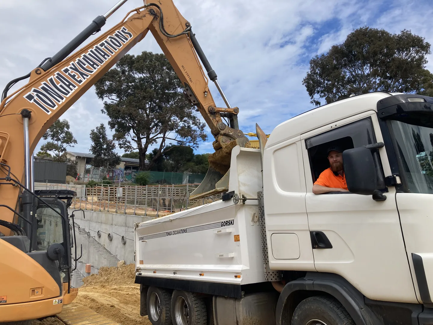 Excavator loading dirt into dump truck at construction site.