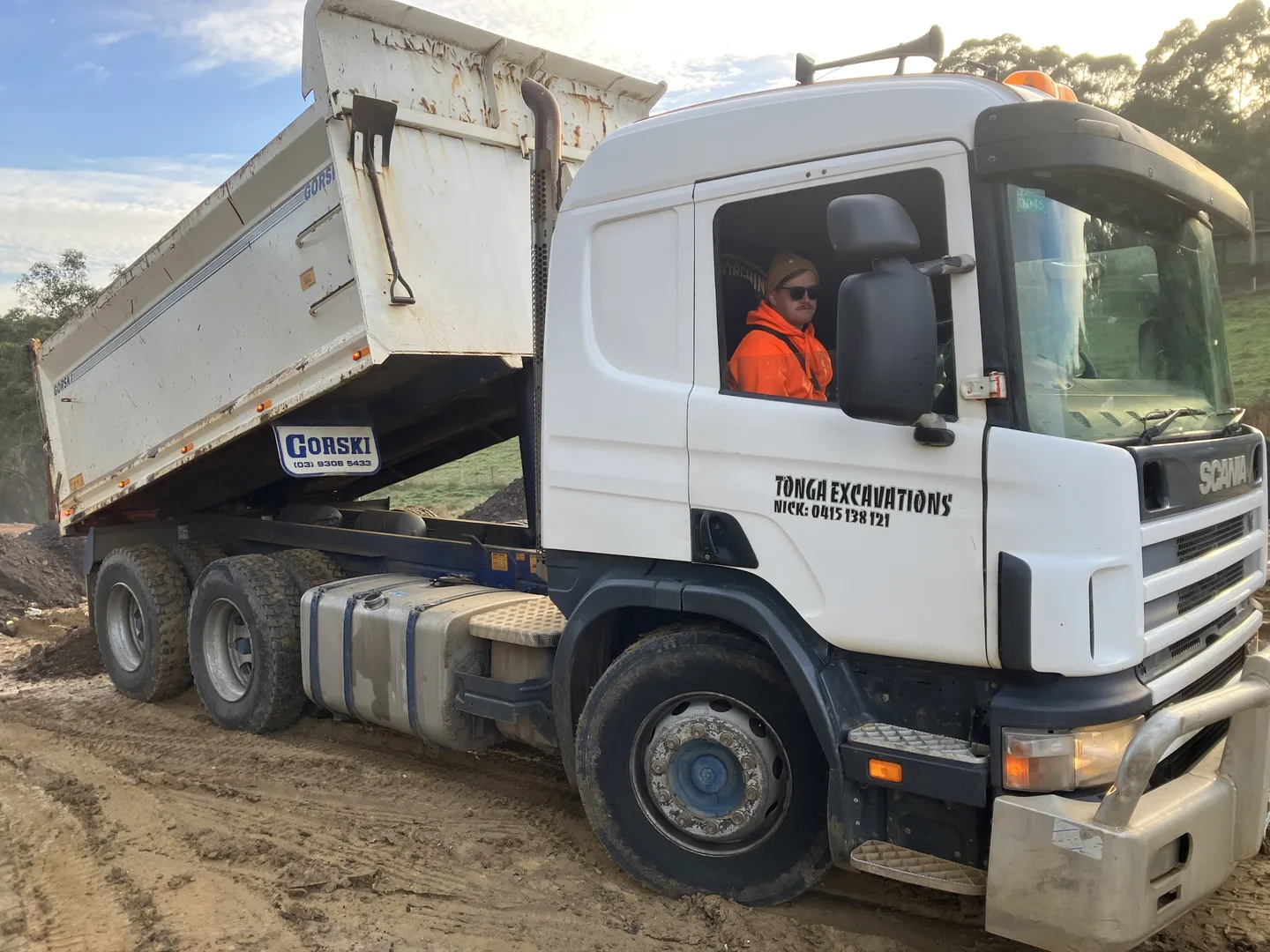 Dump truck at construction site with driver inside.